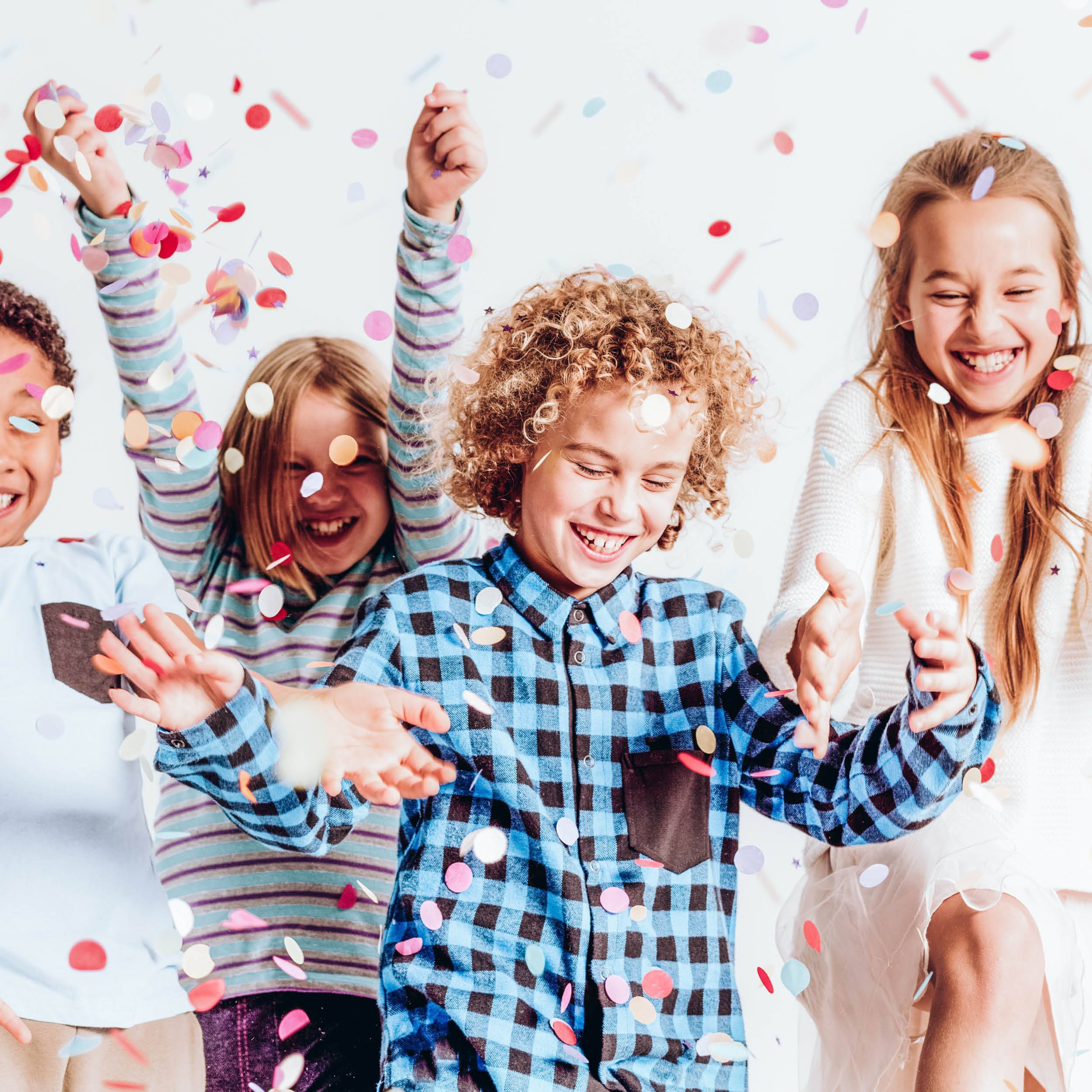 Happy kids dancing amongst confetti